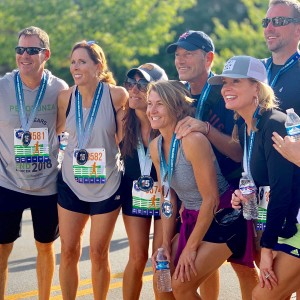Marathon runners posing and smailing for a picture with their race ribbons and medals.
