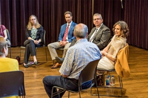Elizabeth Varga sitting in a chair surrounded by peers, having discussions about mental health